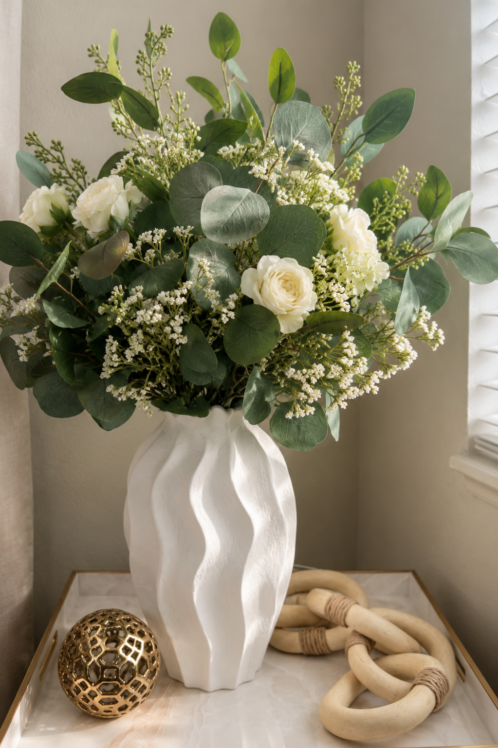 Un set completo, jarrón blanco, decorativo con flores artificiales, una bola dorada. Otra pieza decorativa en madera, una base bandeja en metal, muy elegante.